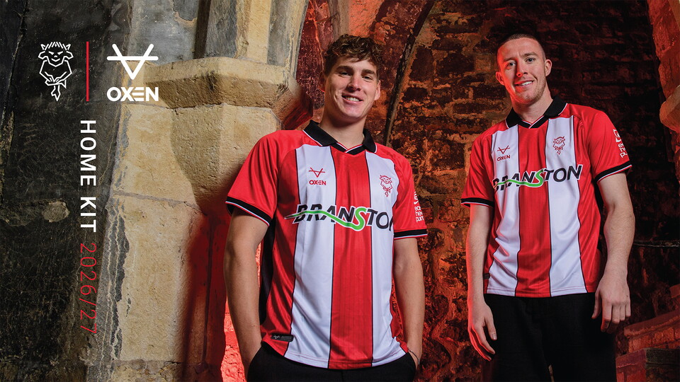 Two men pose wearing red and white striped shirts.