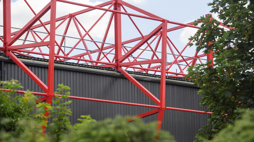 A close up of red steelwork at a football stadium.