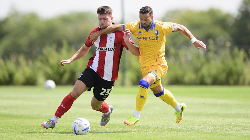 Josh Honohan challenges for the ball under pressure from a Mansfield Town player