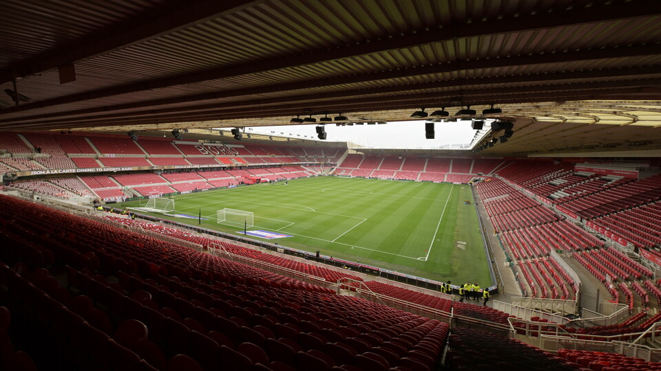 A view of the inside of the Riverside Stadium. There is a green pitch with white football markings, and red seats all around the inner bowl of the stadium.
