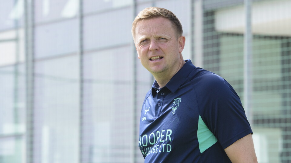 Coach Tom Shaw wears a navy blue top as he looks out
