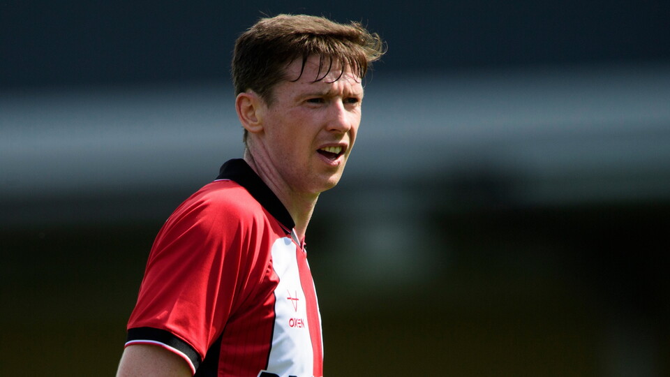 A close-up image of a man in a red and white football shirt.