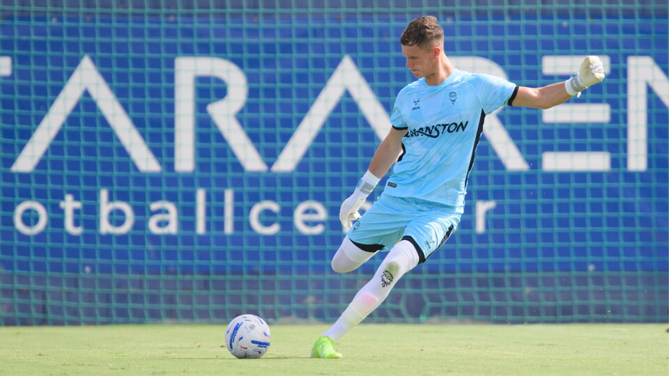 A man in a blue football kit goes to kick the ball.