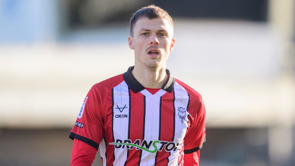A football player in a red and white striped shirt with a blurred background. 