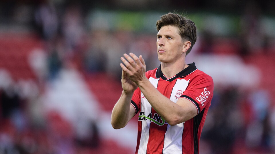 Adam Reach applauds supporters in a red and white shirt.