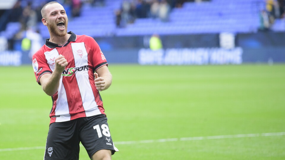 Ben House celebrates with a fistpump. He is stood on a grass football pitch.