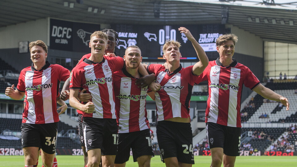 Lincoln City players celebrate as a group after scoring a goal