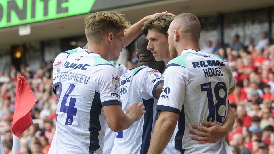 Players wearing white shirts celebrate a goal