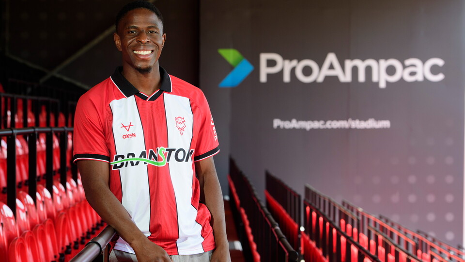 A mani n a red and white striped shirt poses in a football stand