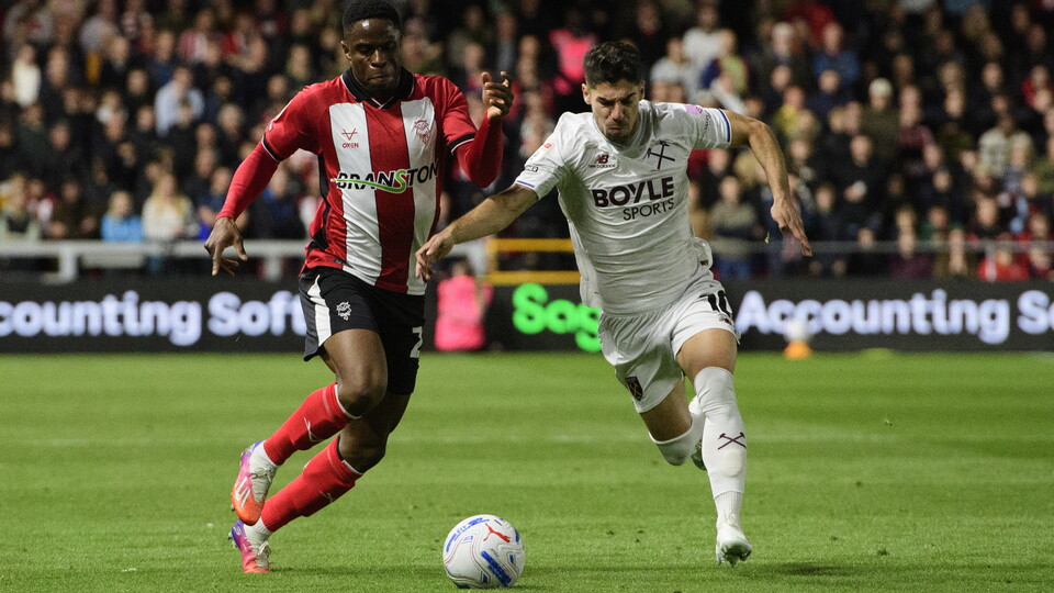 Two players challenge for a football