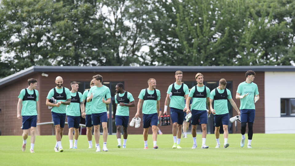 Lincoln City players walk in a line on a football pitch